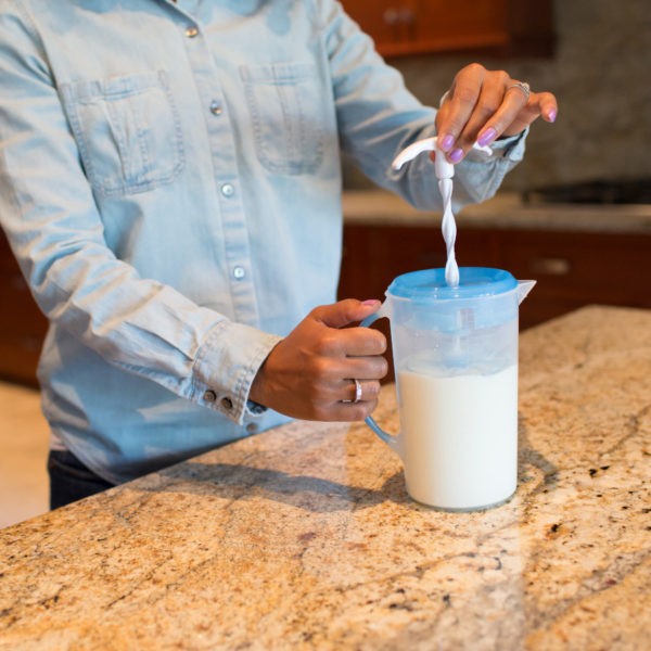 Woman mixing formula mixing pitcher on kitchen counter