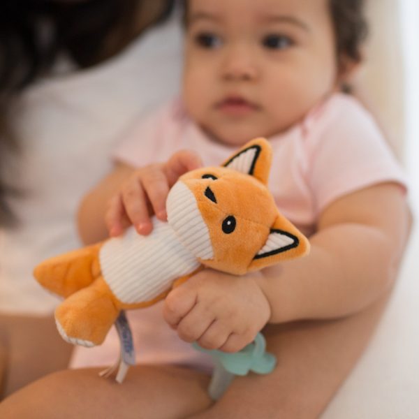 Up close image of baby holding fox lovey pacifier and teether holder