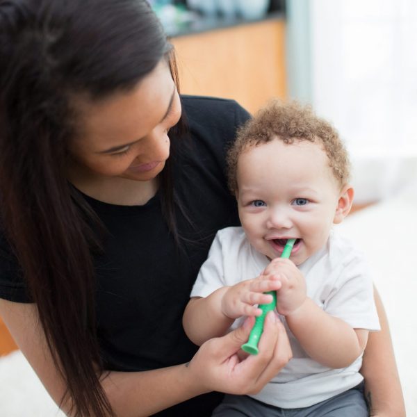 women holding baby and brushing babies teeth
