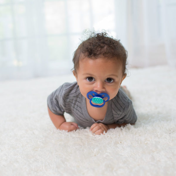 Baby with Pacifier lying on rug