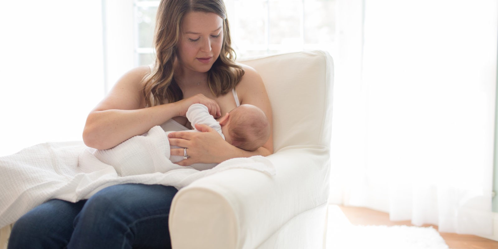 Woman sitting in chair breastfeeding baby