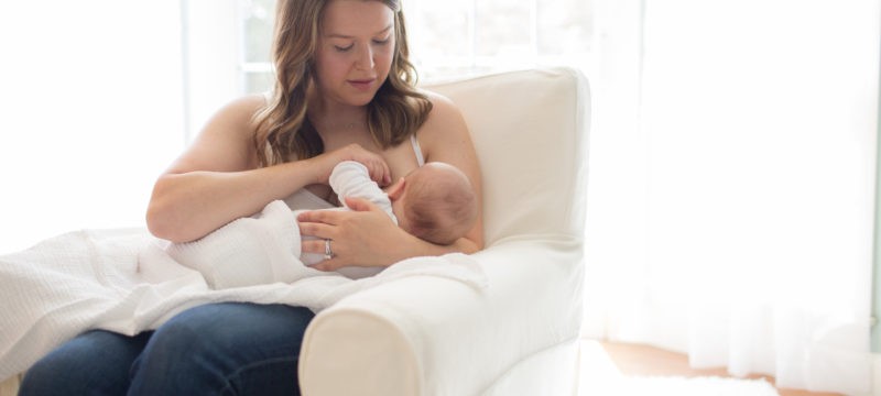 Woman sitting in chair breastfeeding baby