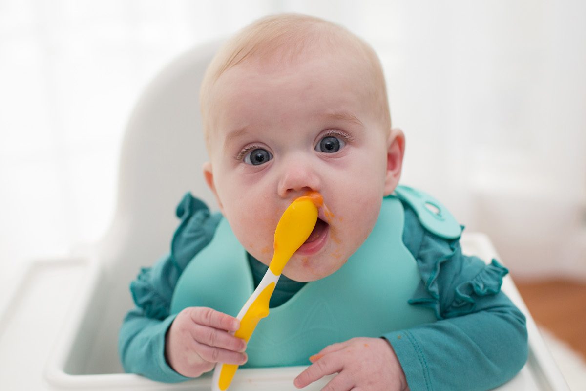 6 month old baby holding spoon eating