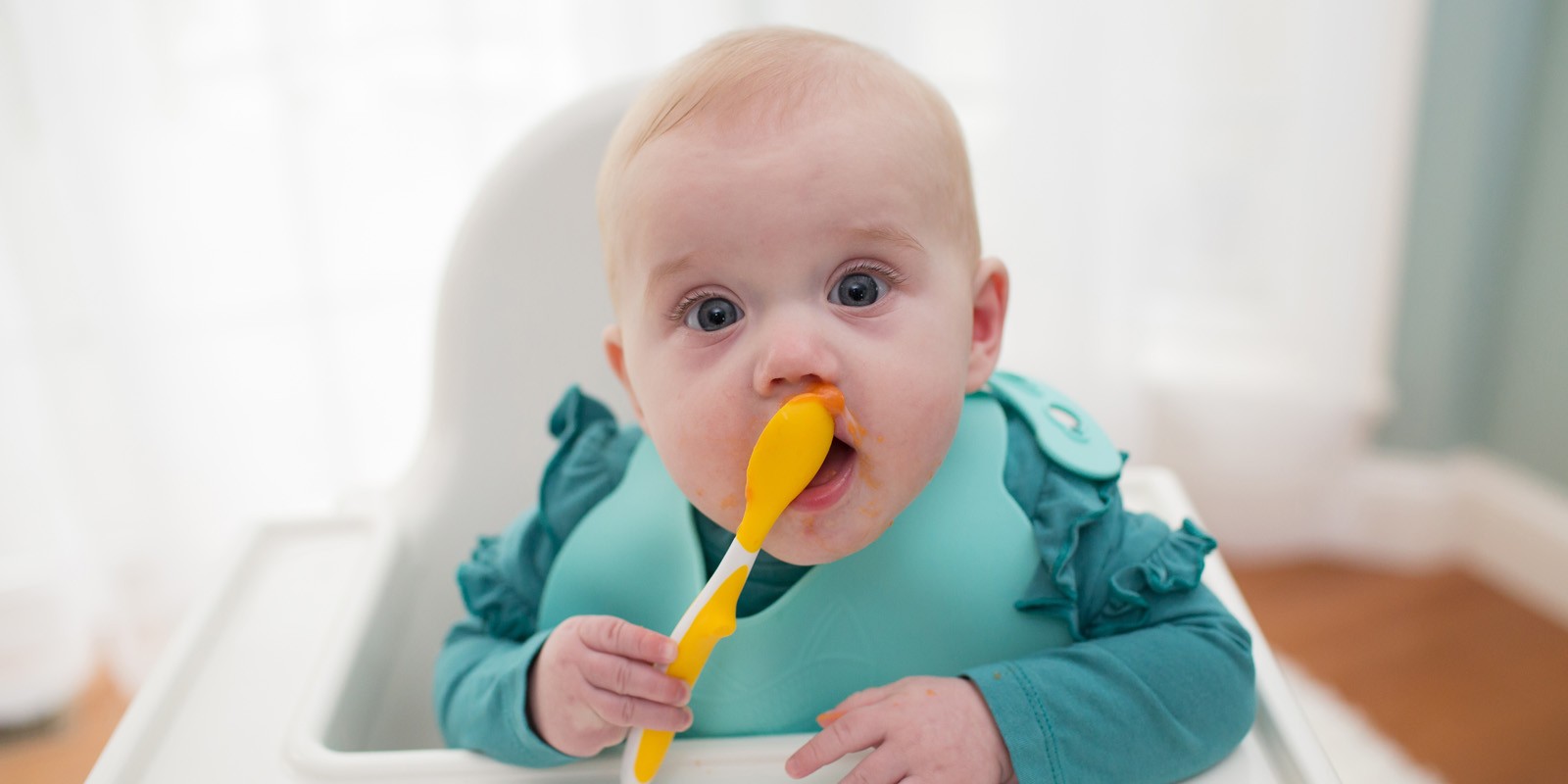6 month old baby holding spoon eating