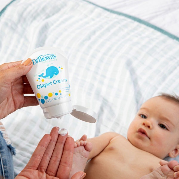 Dr. Brown's Diaper Cream in a mom's hands with a baby on a bed