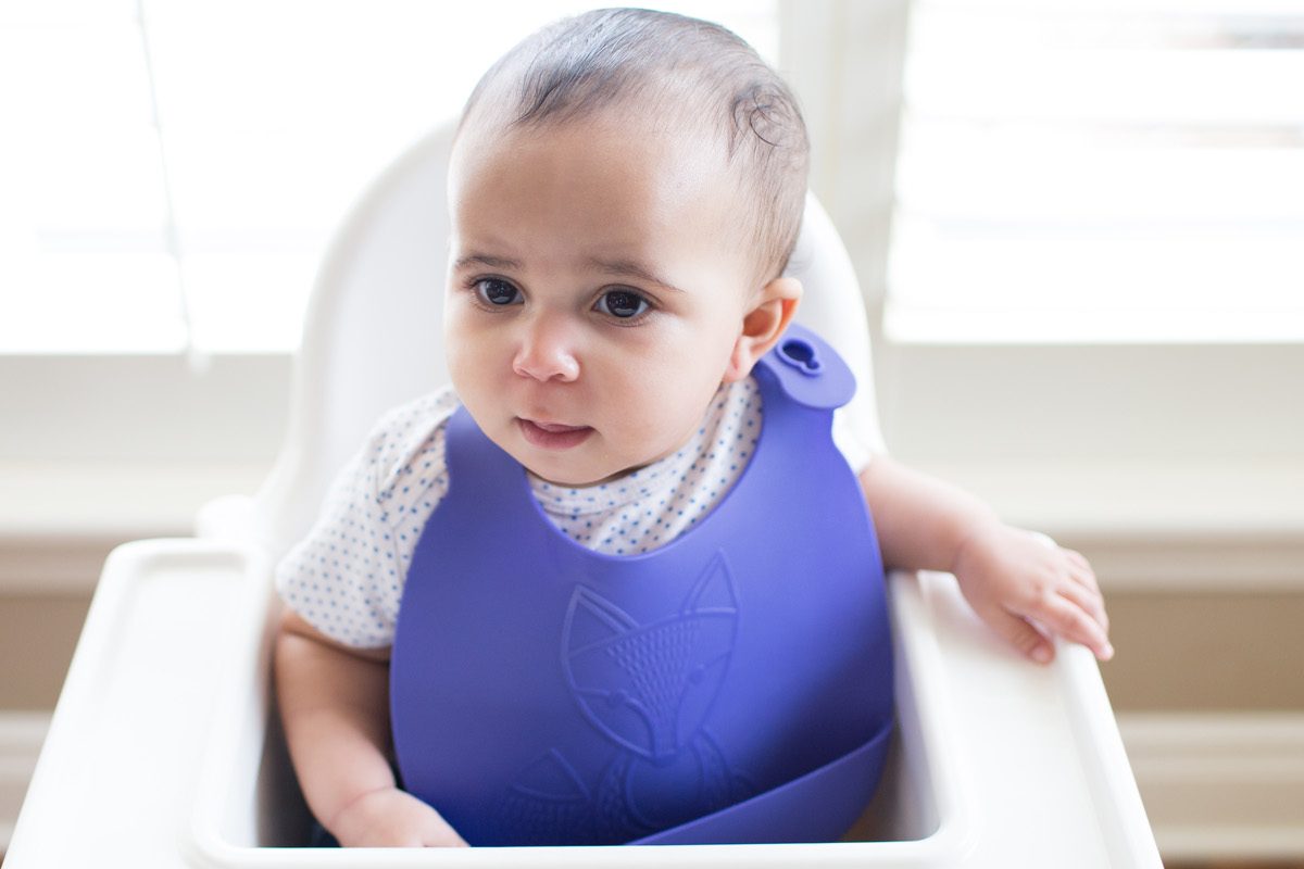 Toddler at high chair with silicone bib