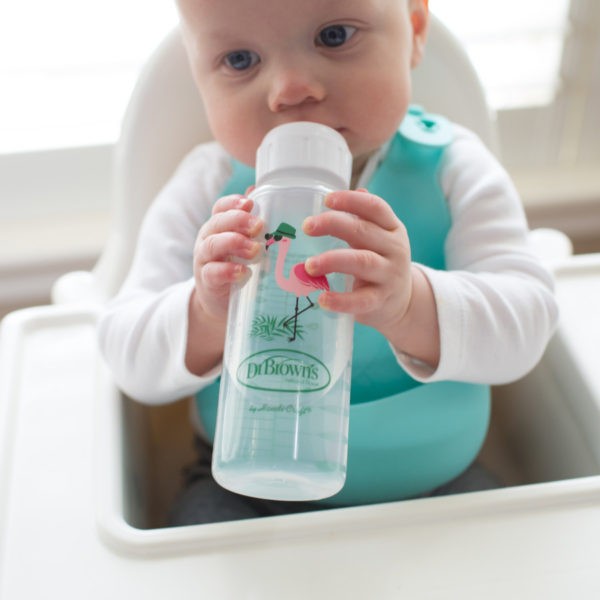 Baby in high chair drinking from flamingo sippy bottle