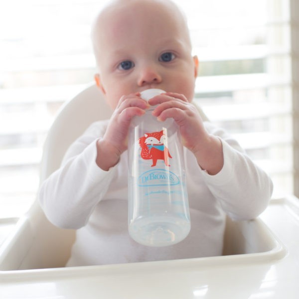 Baby in high chair drinking from fox sippy bottle