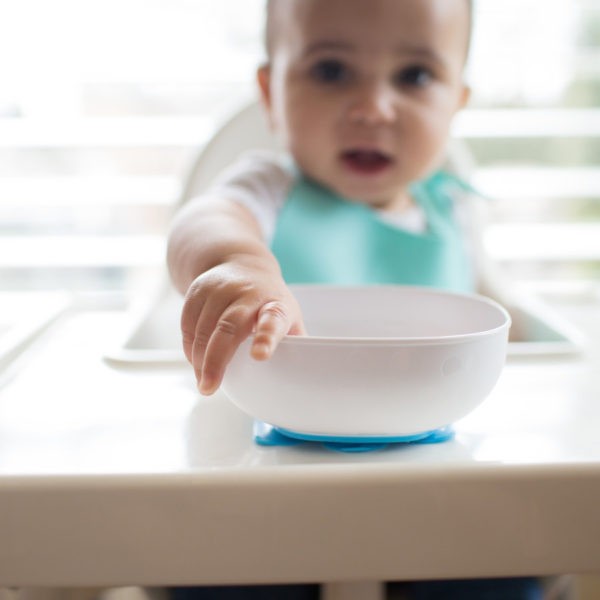 Upclose photo of baby in high chair pulling on suction bowl