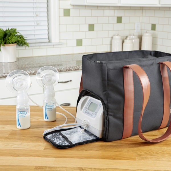 Black pump bag on kitchen counter with pump zipper pocket open, collection kits with milk in bottle next to pump