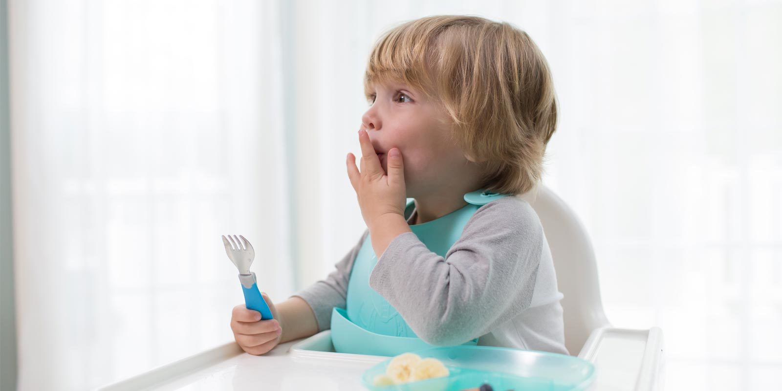 Toddler with a divided plate and soft-grip spoon and fork