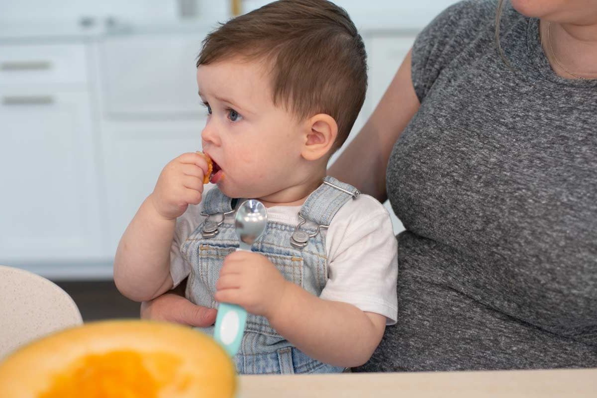 Toddler eating cantaloupe with teal soft-grip spoon