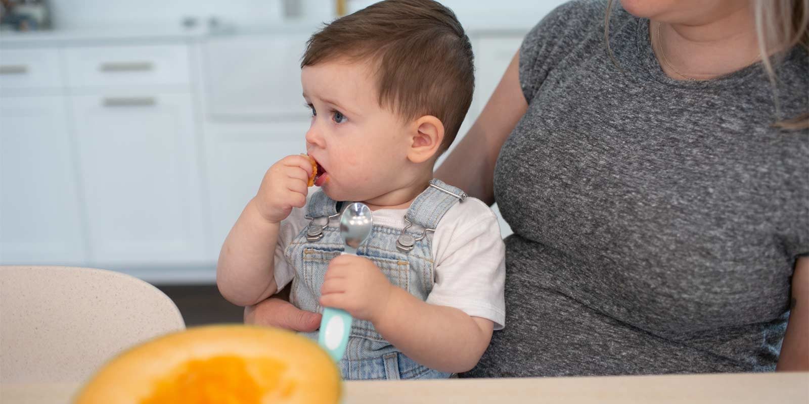 Toddler eating cantaloupe with teal soft-grip spoon
