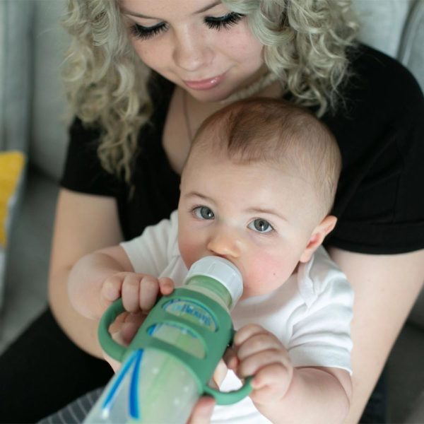 Parent holding a baby with a sippy bottle with green Narrow Silicone Handles
