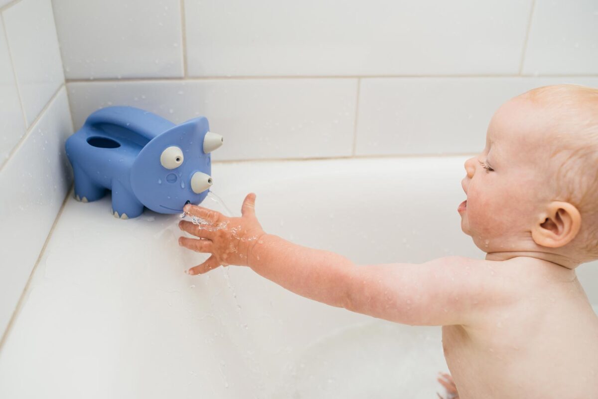 Infant playing with Pour and Roar Triceratops Bath Toy
