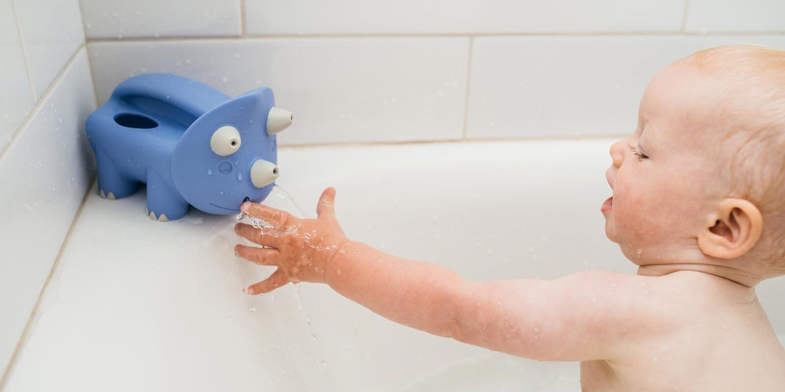 Infant playing with Pour and Roar Triceratops Bath Toy