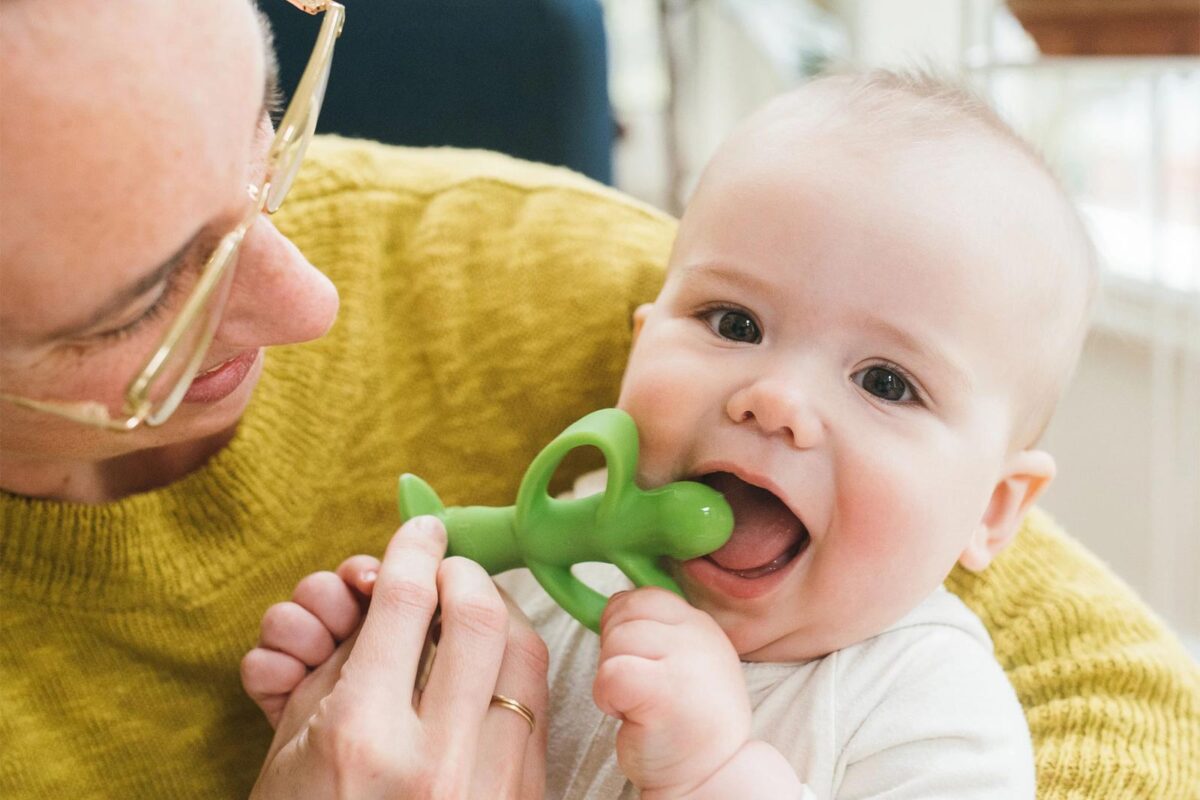 Parent helping infant with peapod teether