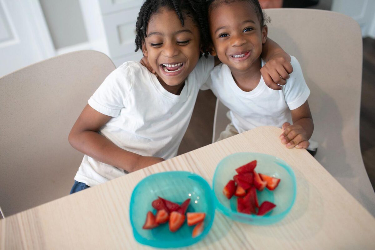 Two toddlers in front of bowls of strawberries