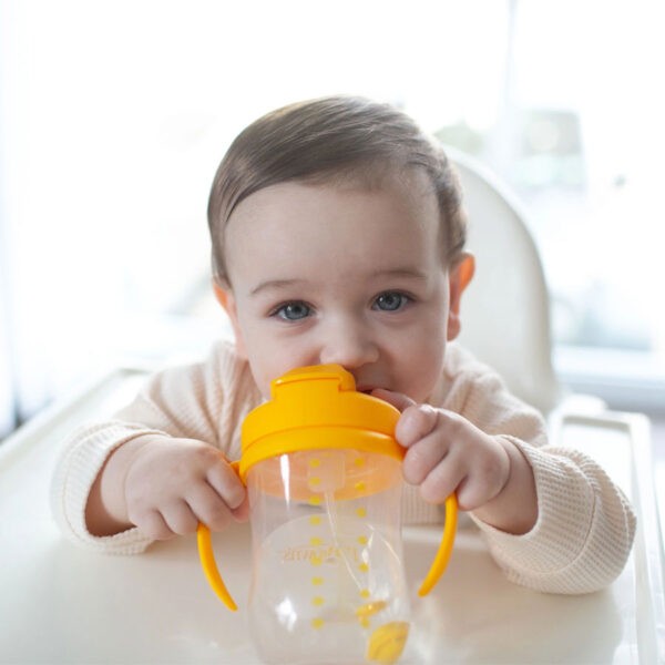 Infant holding a vintage yellow straw cup