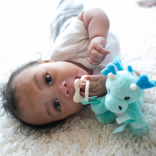 Infant on floor with Dragon Lovey and ecru pacifier
