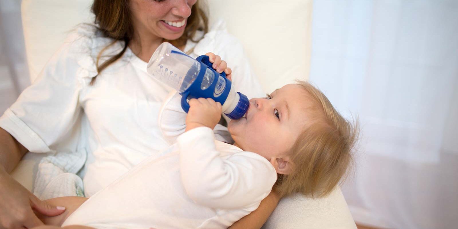 Parent holding baby drinking from sippy bottle