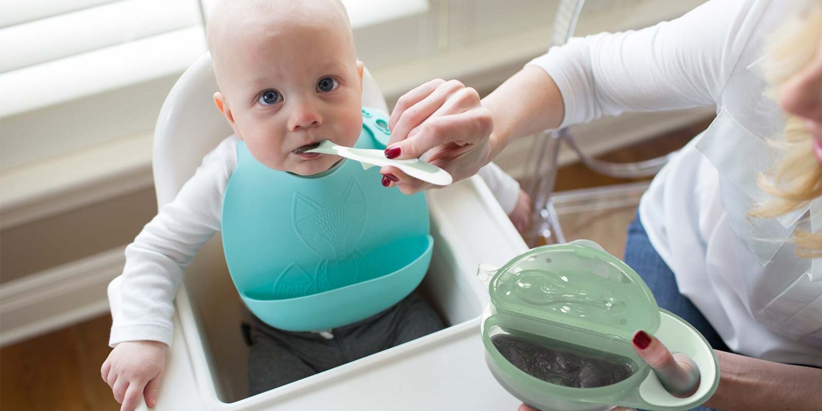 Infant being fed with bowl and light green spoon