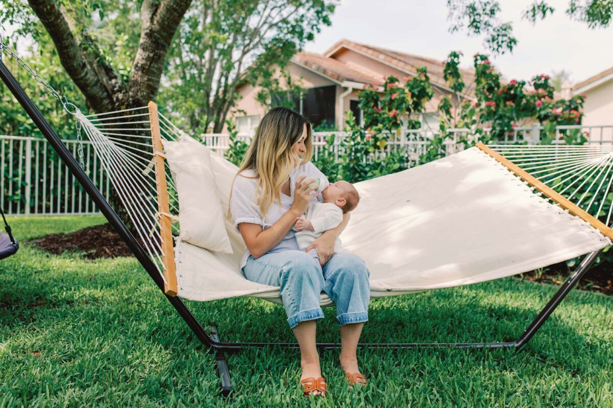 Parent feeding baby with a bottle on a hammock