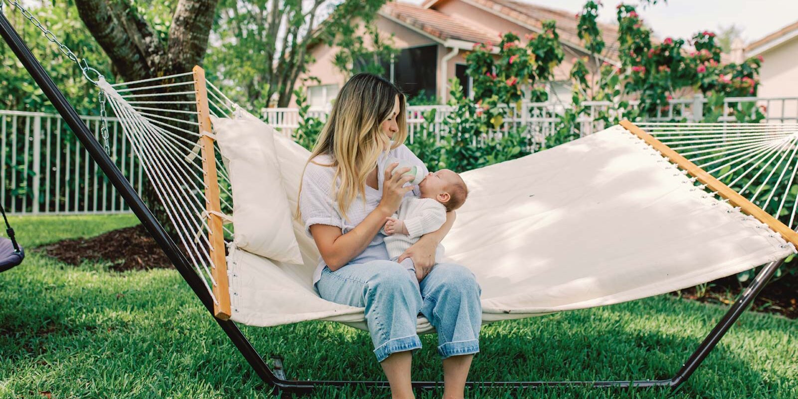 Parent feeding baby with a bottle on a hammock