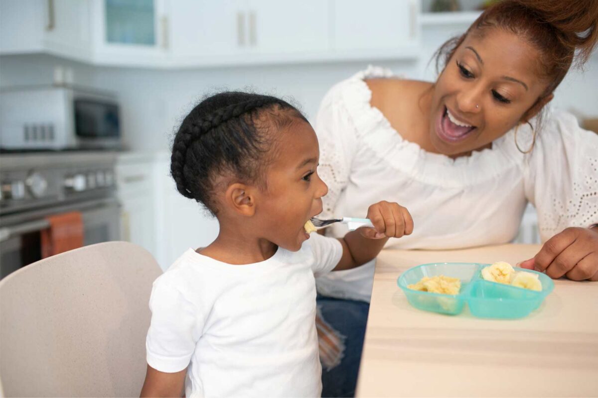 Parent with toddler, eating with soft grip fork out of divided plate