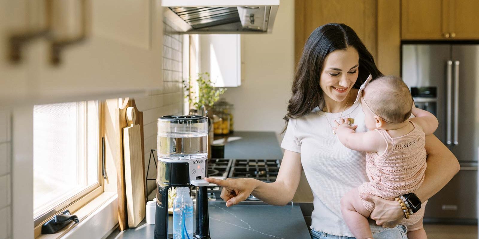 Parent using Insta-Prep Water Dispenser while holding infant