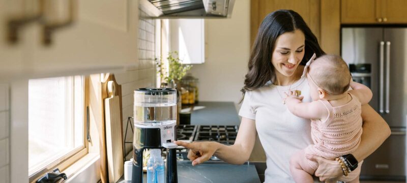 Parent using Insta-Prep Water Dispenser while holding infant