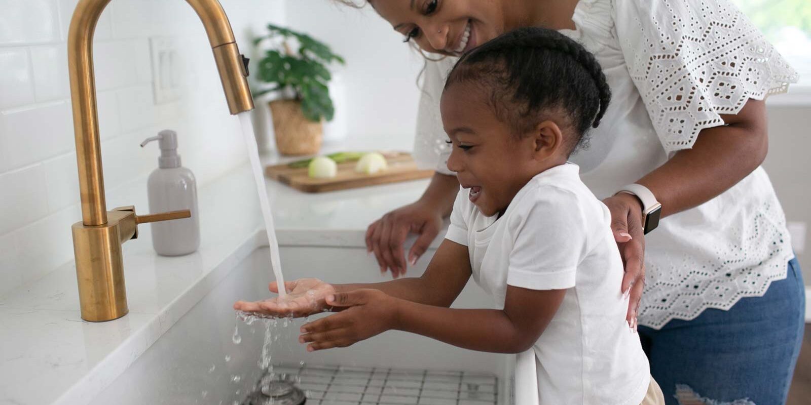 Parent and toddler in kitchen washing hands