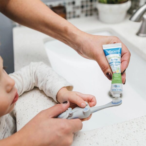 Parent putting baby toothpaste on toothbrush