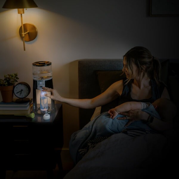 Parent at night filling bottle using Insta-Prep Warm Water Dispenser