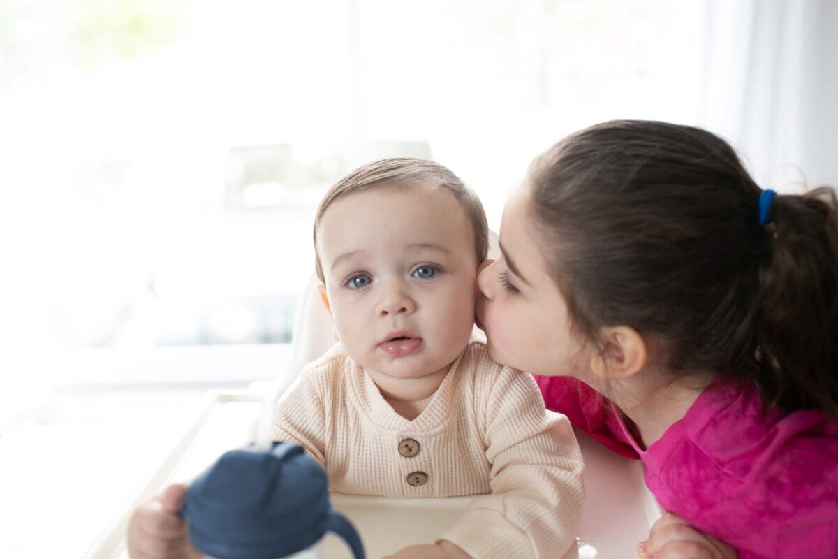Toddler kissing newborn sibling