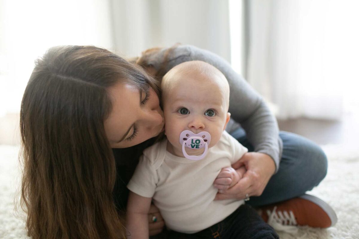 Parent kissing infant with Advantage pacifier