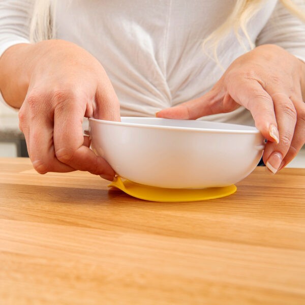 Up close image of woman pulling suction bowl tab off of counter top to release suction