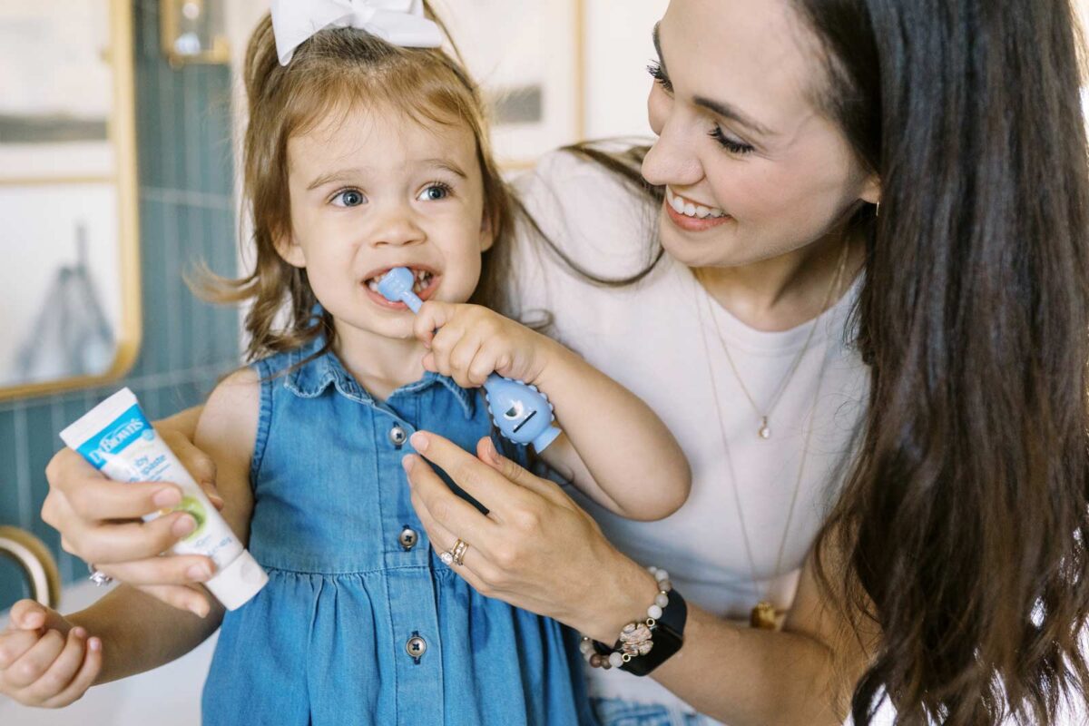 Parent helping toddler brush their teeth