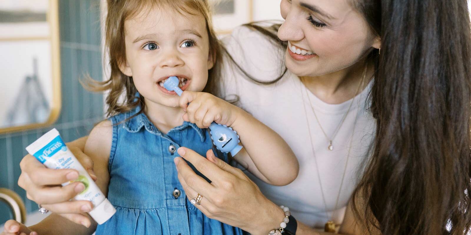 Parent helping toddler brush their teeth