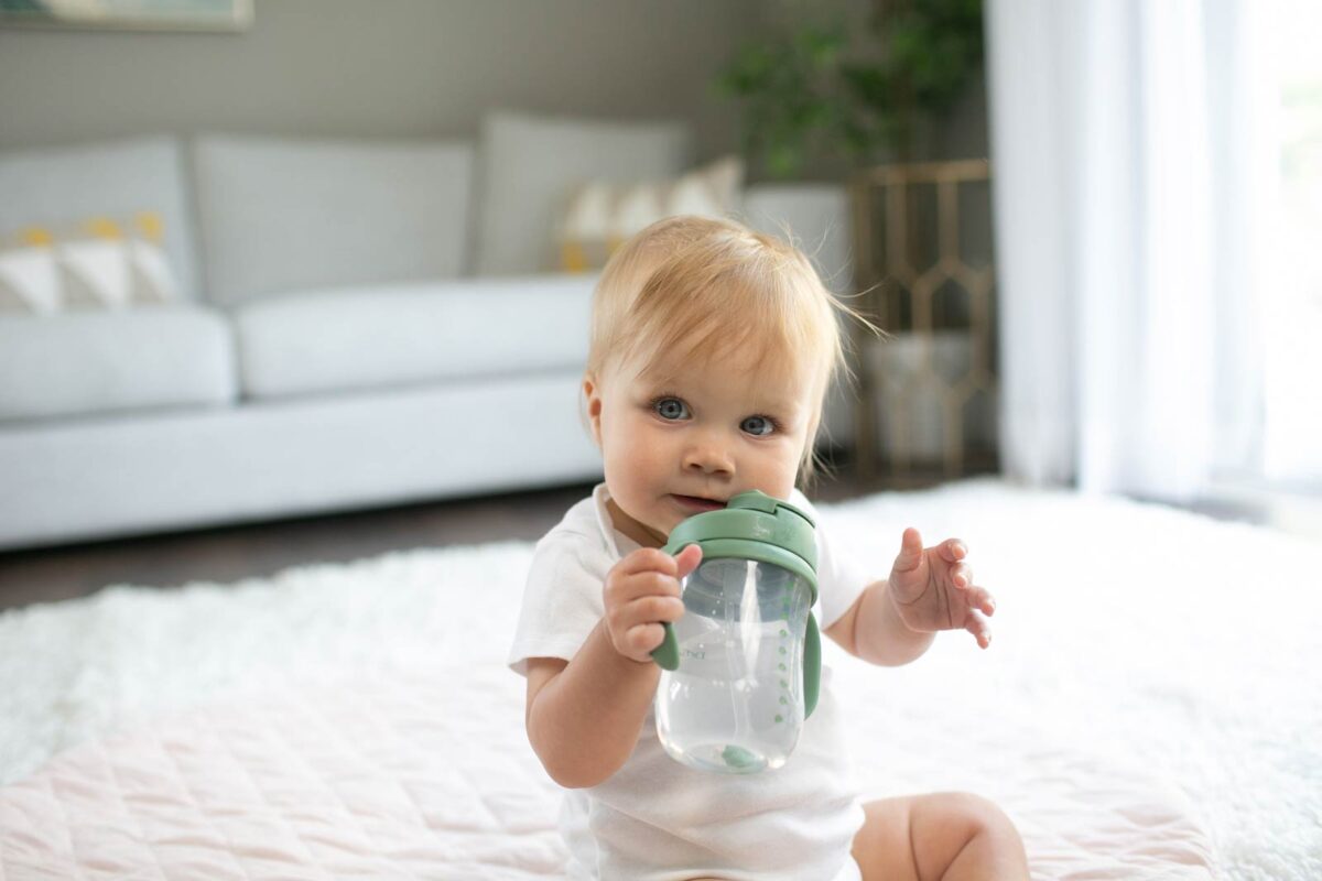 Baby with holding a green straw cup