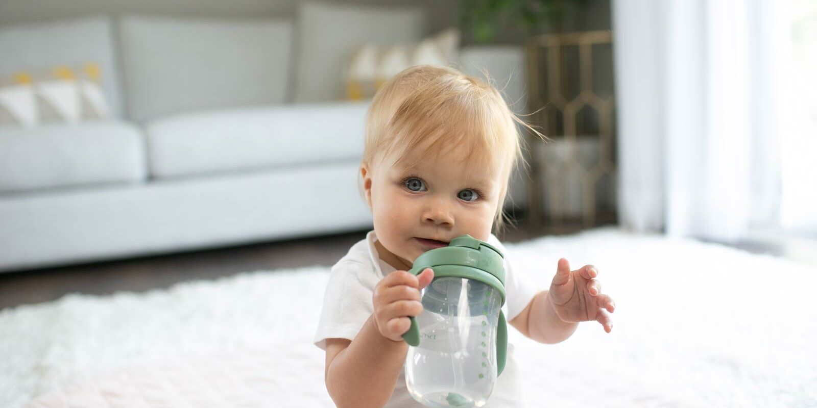 Baby with holding a green straw cup