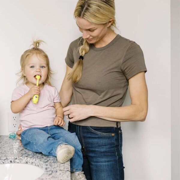 Parent with toddler brushing teeth with Green Monster Toddler Toothbrush